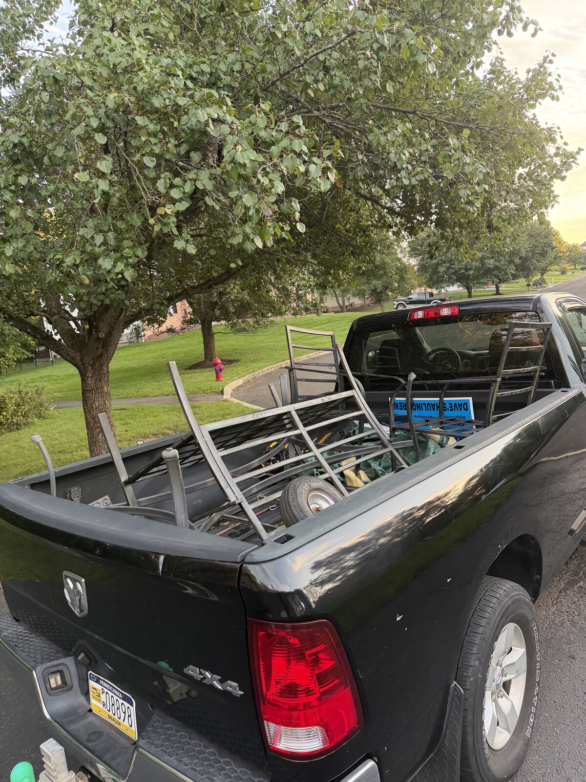 Black pickup bed loaded with metal furniture frames and a hand truck