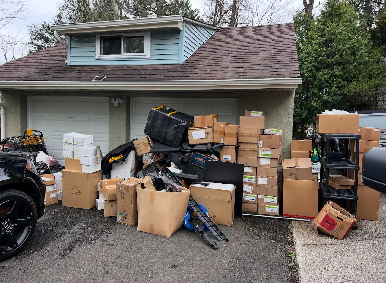 Boxes, furniture, and other household belongings in front of a garage before removal