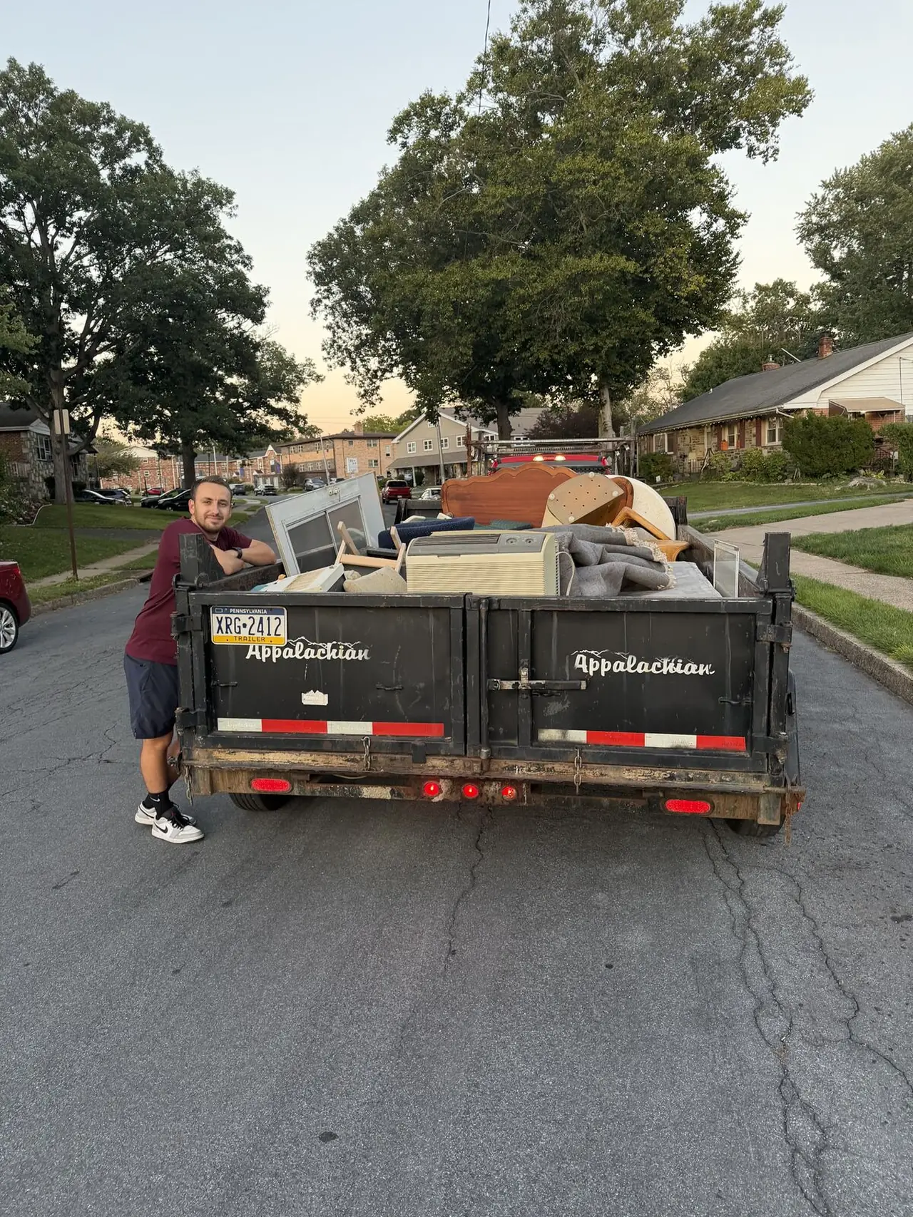 Crew member standing beside a trailer loaded with household items