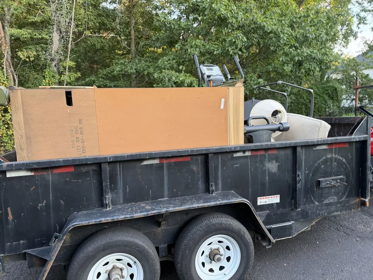 Dump trailer loaded with furniture, an elliptical machine, and household items